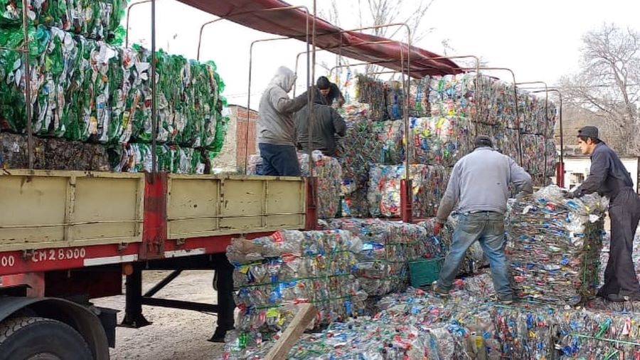 trabajadores de la planta de reciclaje trasladando plastico