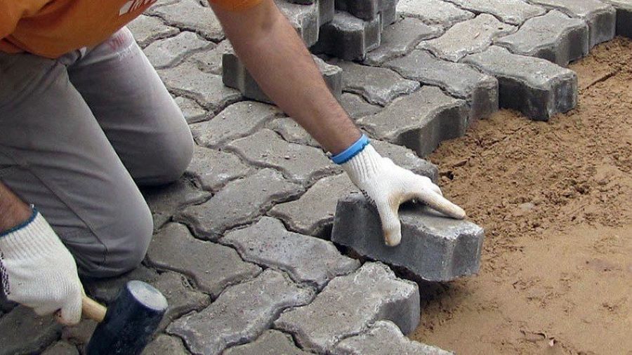 Mano de obrero colocando adoquines de hormigón en Mendiolaza